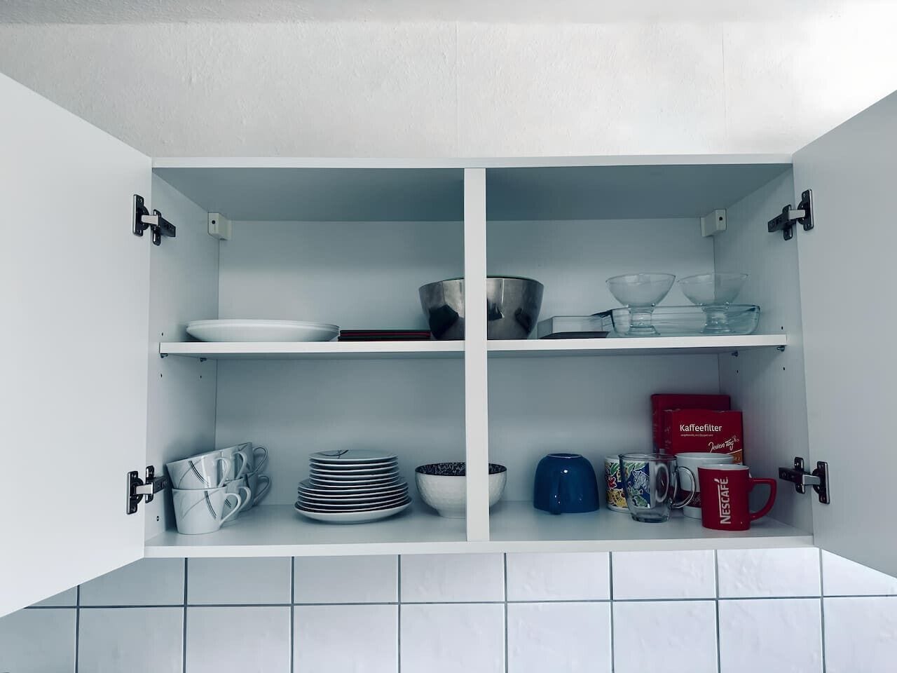 Ein weißer Küchenschrank mit vier Einlegebögen, auf denen verschiedene Küchenutensilien stehen.