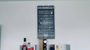 Una repisa de cocina con diversos objetos, incluyendo botellas, un organizador de especias y un cartel con texto.