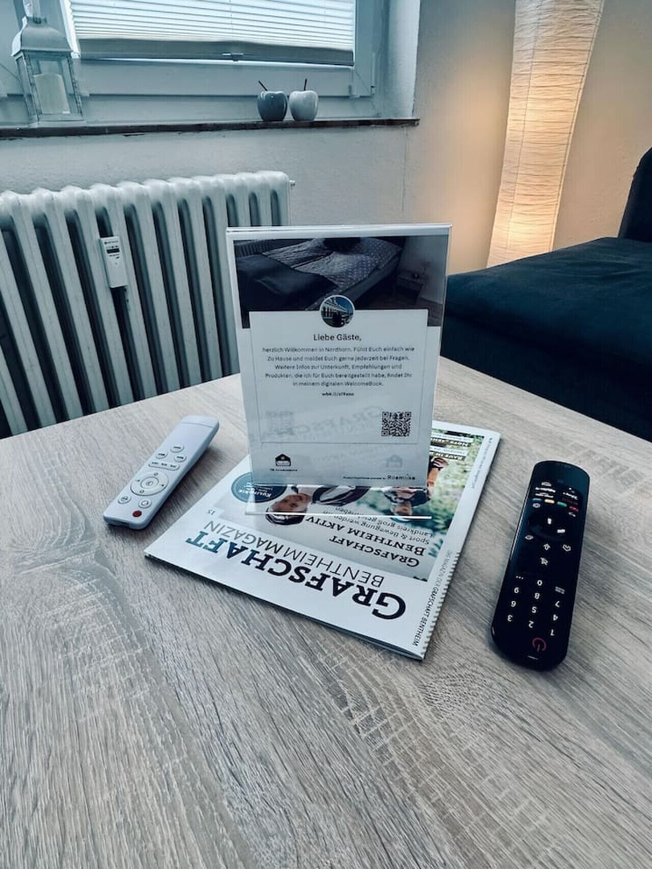 Una mesa con un control remoto, un folleto y un periódico impreso.