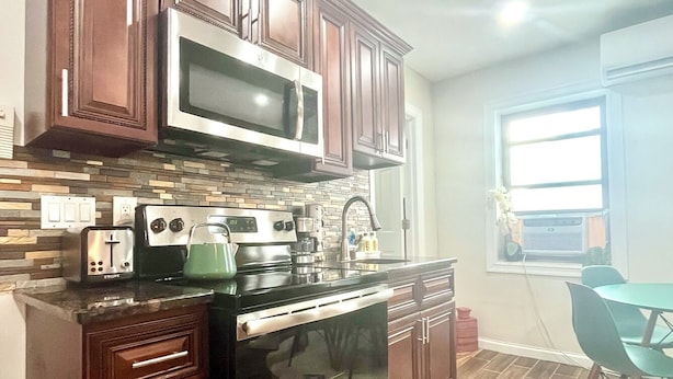 A kitchen with dark wooden cabinets, a stainless steel microwave, a stove, and a dishwasher.