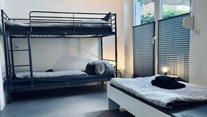 Quarto com beliche, janela e mesa de cabeceira.