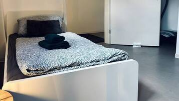 Ein modernes Schlafzimmer mit einem Bett, einer Tür und einem gerahmten Schild mit der Aufschrift 'HAPPY'.