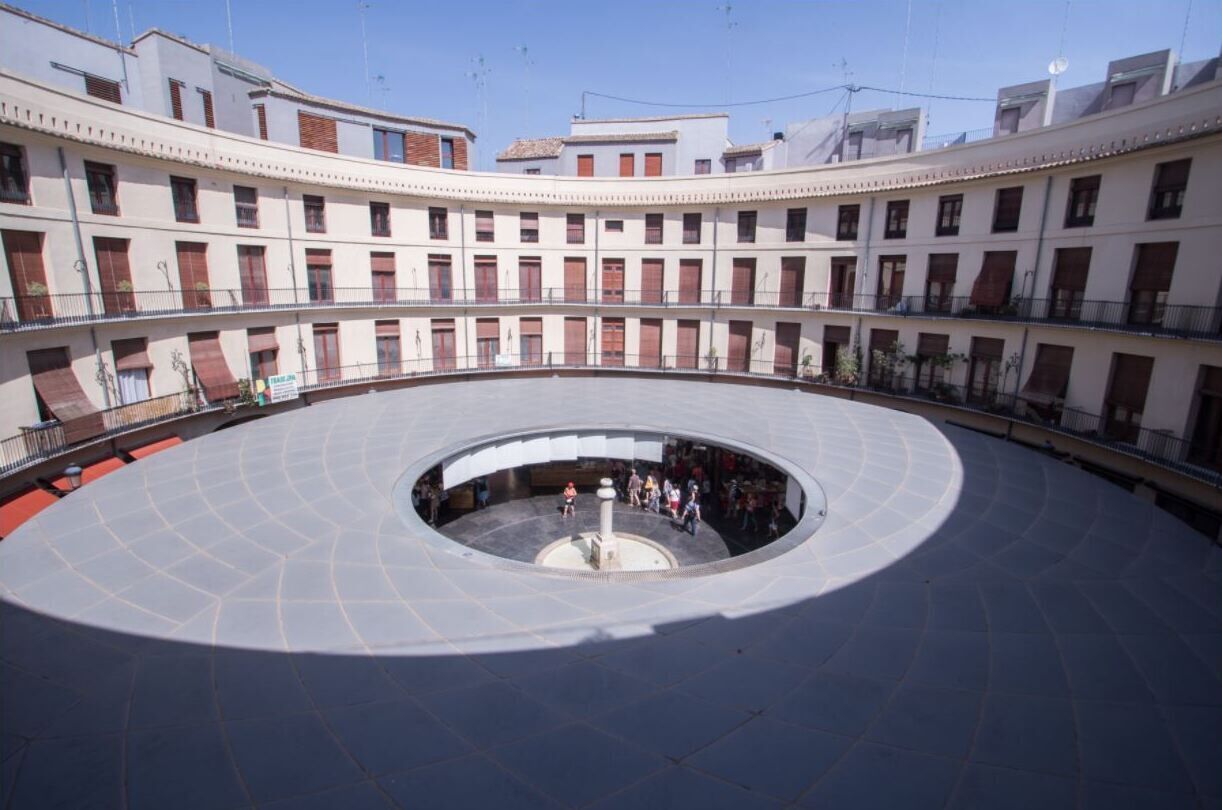 A circular courtyard with a central fountain, surrounded by multi-story buildings with balconies.