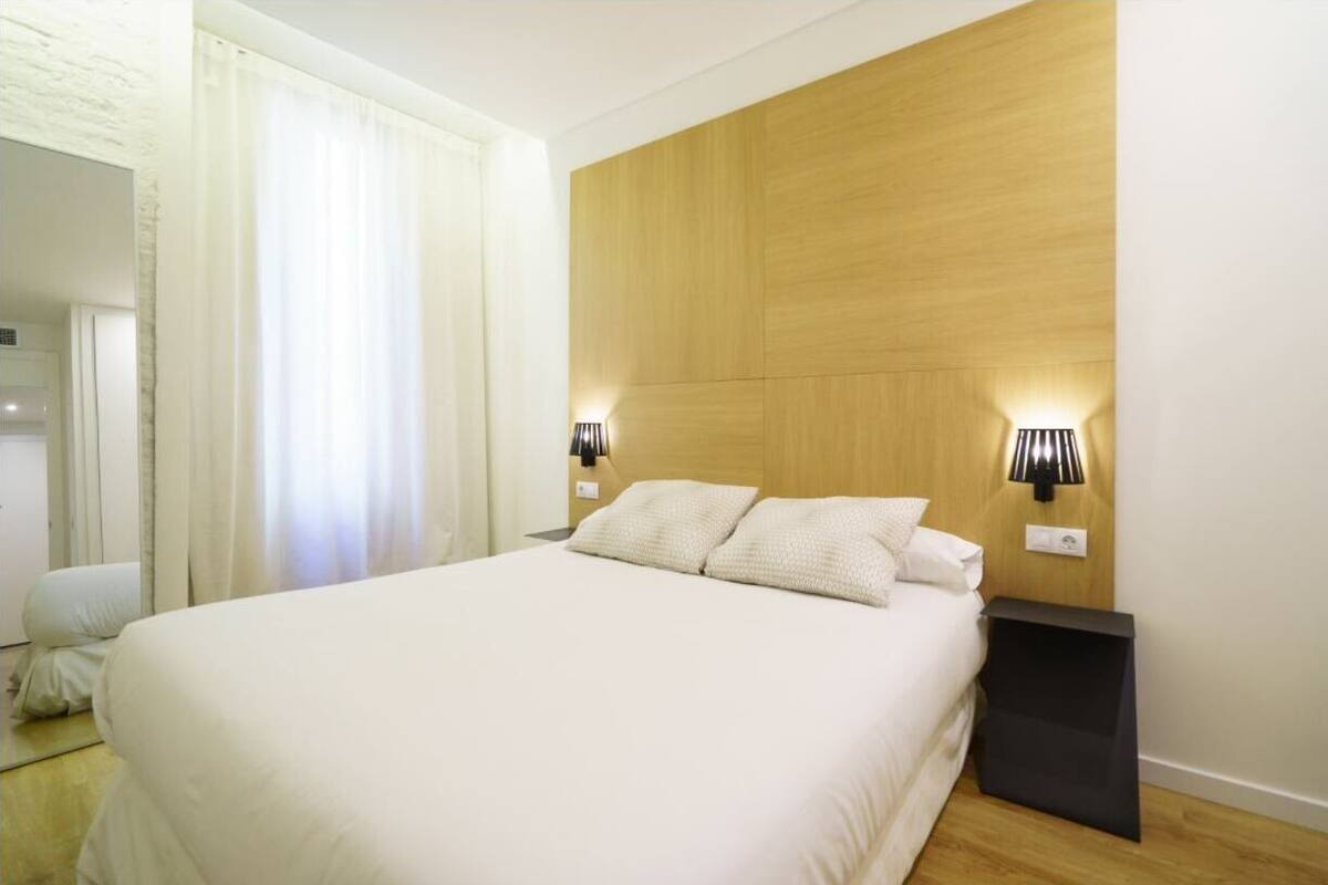 A neatly made bed with white linens in a modern hotel room.
