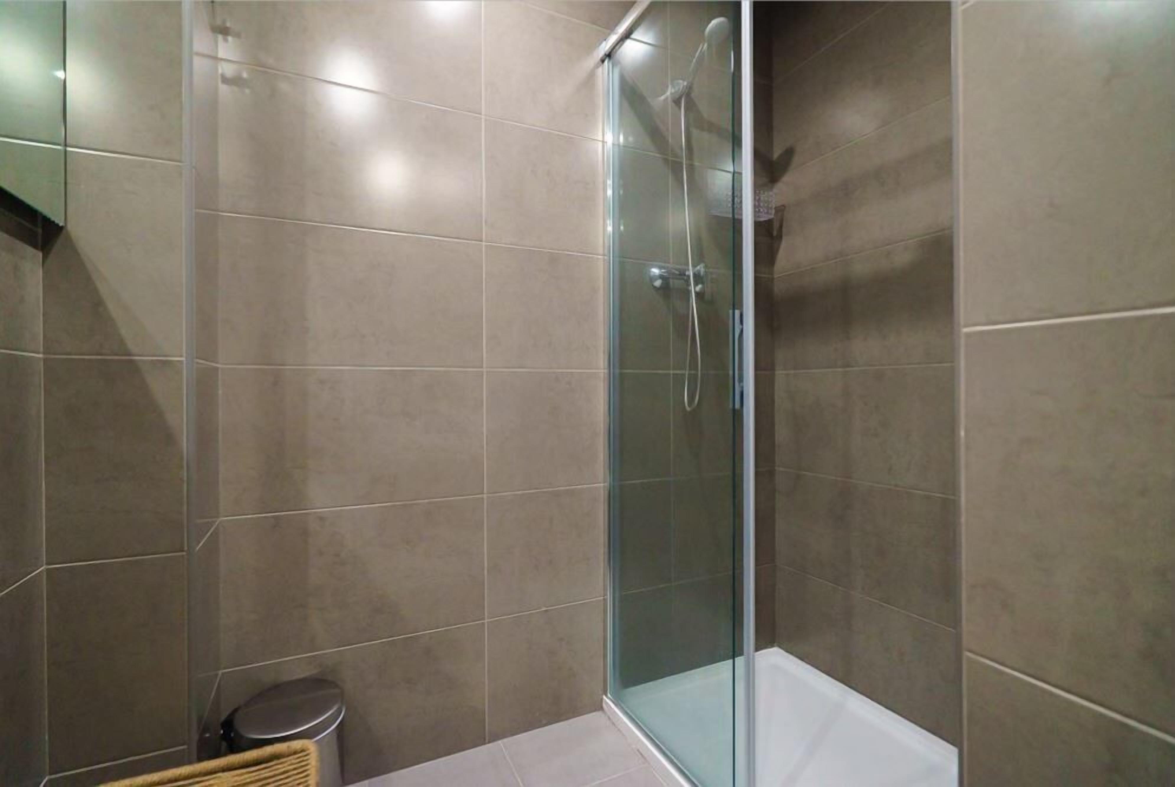A modern bathroom with a glass-enclosed shower, a toilet, and a bathtub.