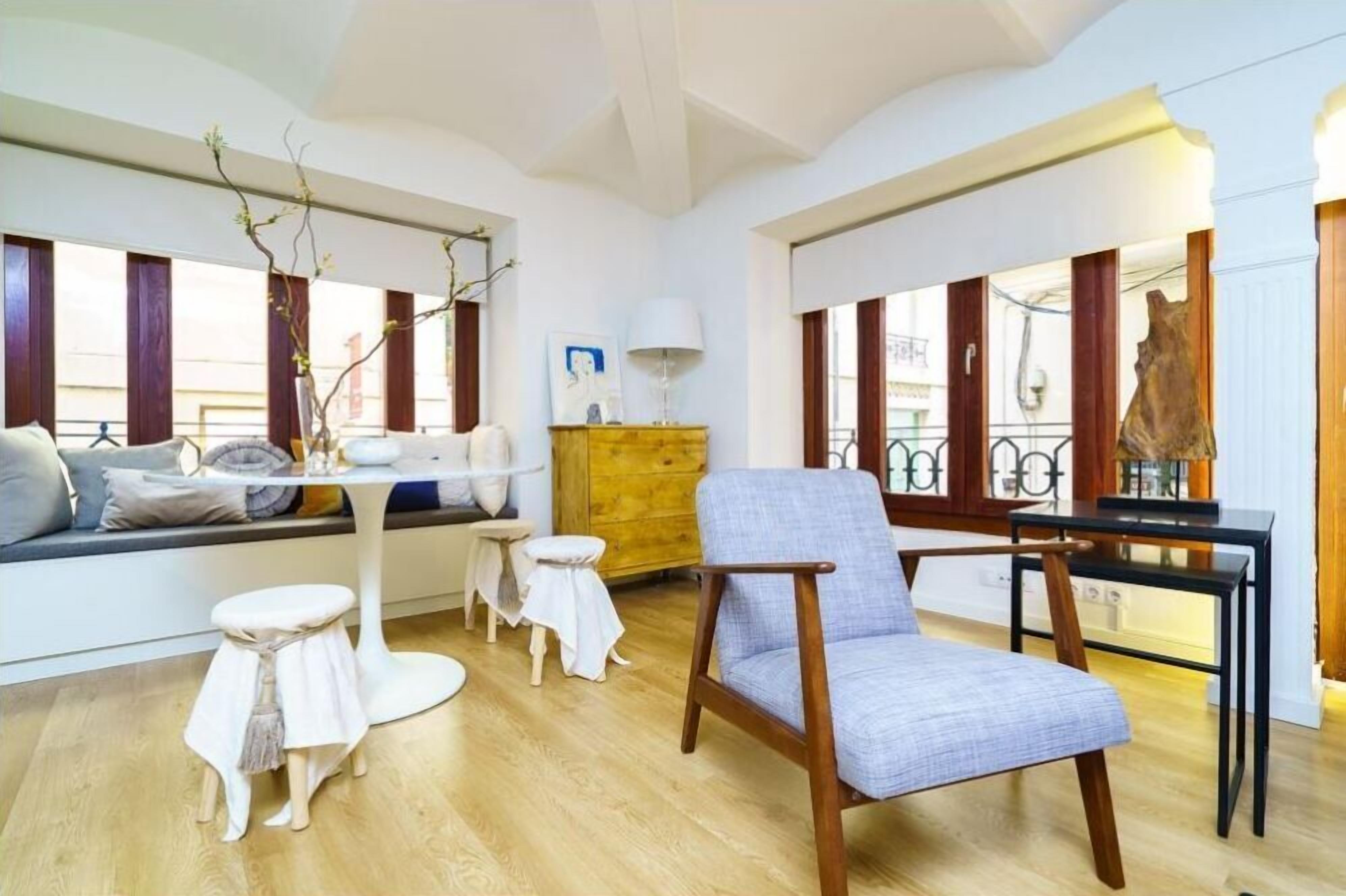 Una sala moderna con un sofá, un sillón azul, una mesa de centro de madera y una mesita auxiliar.