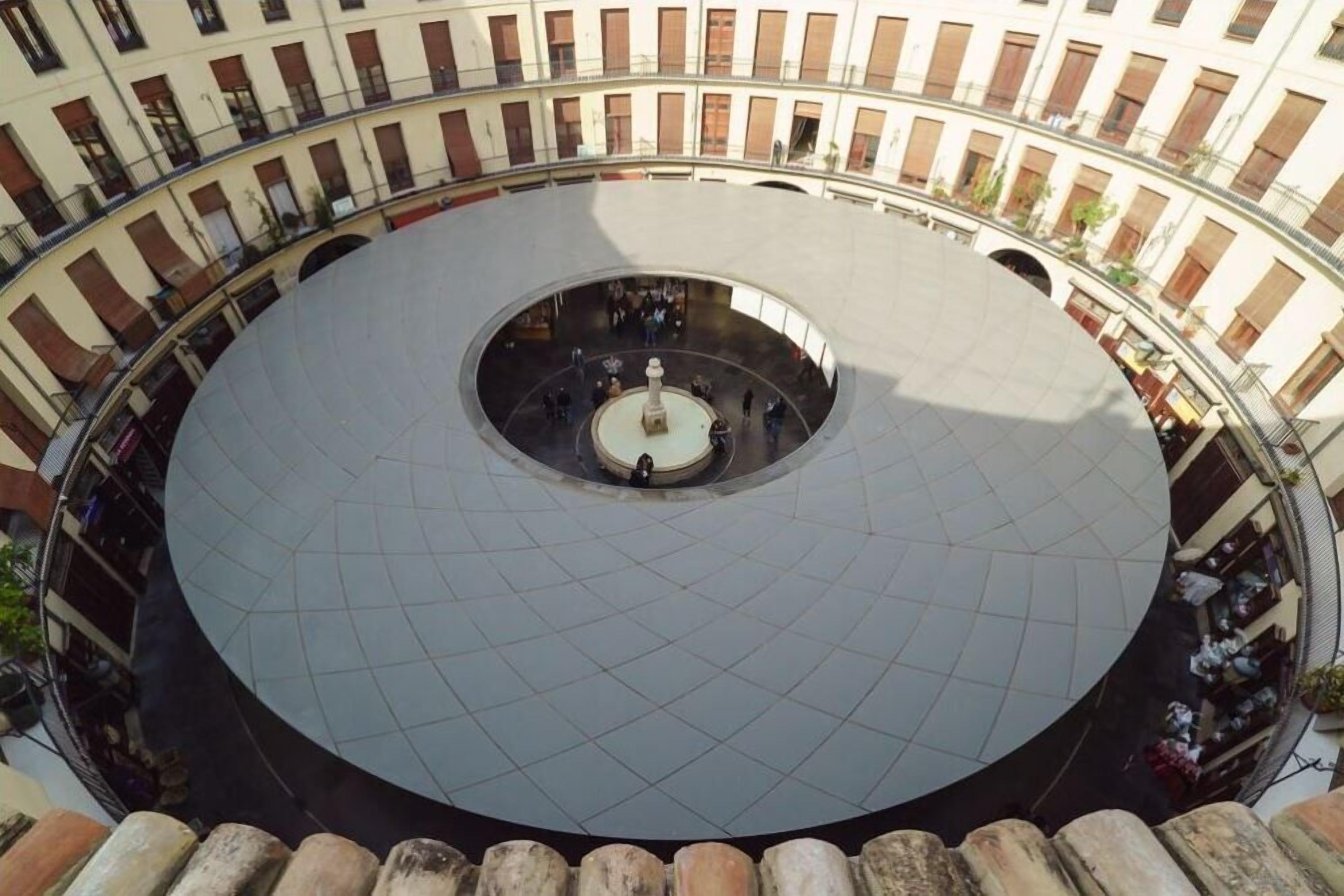 A circular courtyard with a central fountain, surrounded by buildings with balconies and windows.