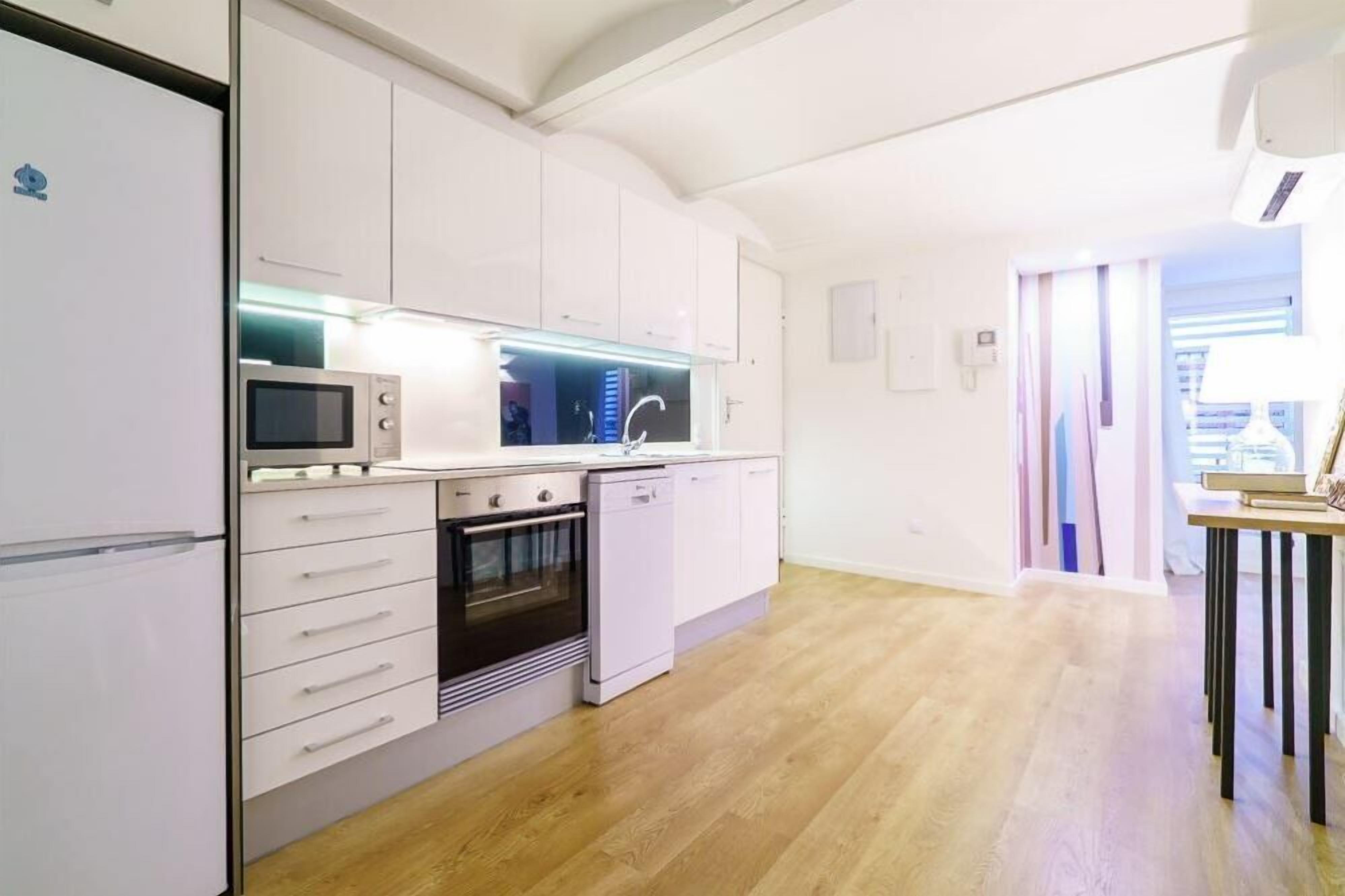 A modern kitchen with white cabinets, a microwave, an oven, and a dishwasher.