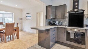 Een moderne keuken met een ingebouwde oven, magnetron en een roestvrijstalen afzuigkap.