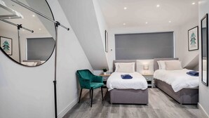 A modern bedroom with two beds, a desk, a chair, and a large mirror. - Spacious, High Spec & Modern (Woodseats)