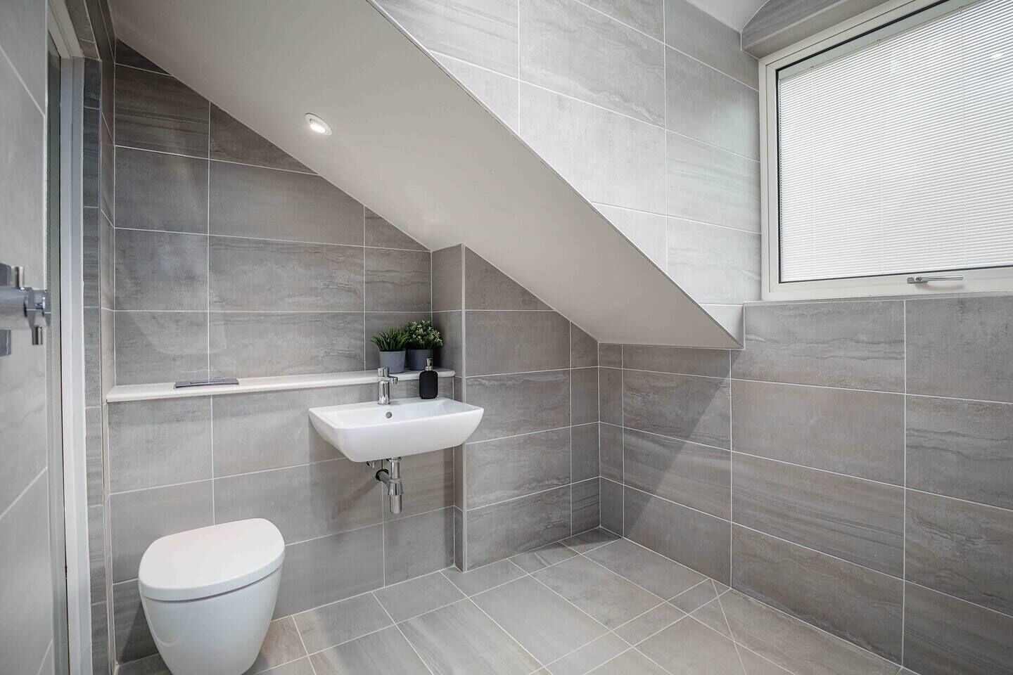 A modern bathroom with a white sink, a toilet, and a shower area.