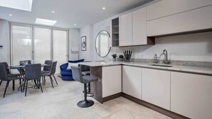 A modern kitchen with a dining area, featuring a round table, chairs, and a blue sofa. - Spacious, High Spec & Modern (Woodseats)