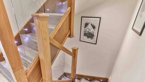 A wooden staircase with glass railings and a framed abstract art piece on the wall. - Spacious, High Spec & Modern (Woodseats)