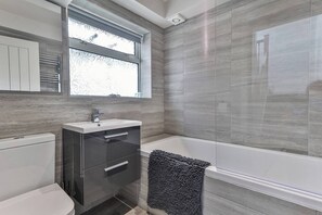 A modern bathroom with a toilet, sink, and bathtub.
