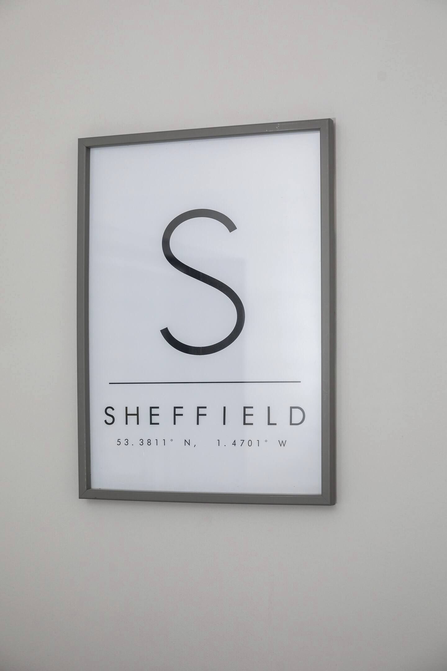 A framed sign with a large 'S' and the word 'SHEFFIELD' along with coordinates.