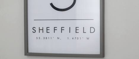 A framed sign with a large 'S' and the word 'SHEFFIELD' along with coordinates.