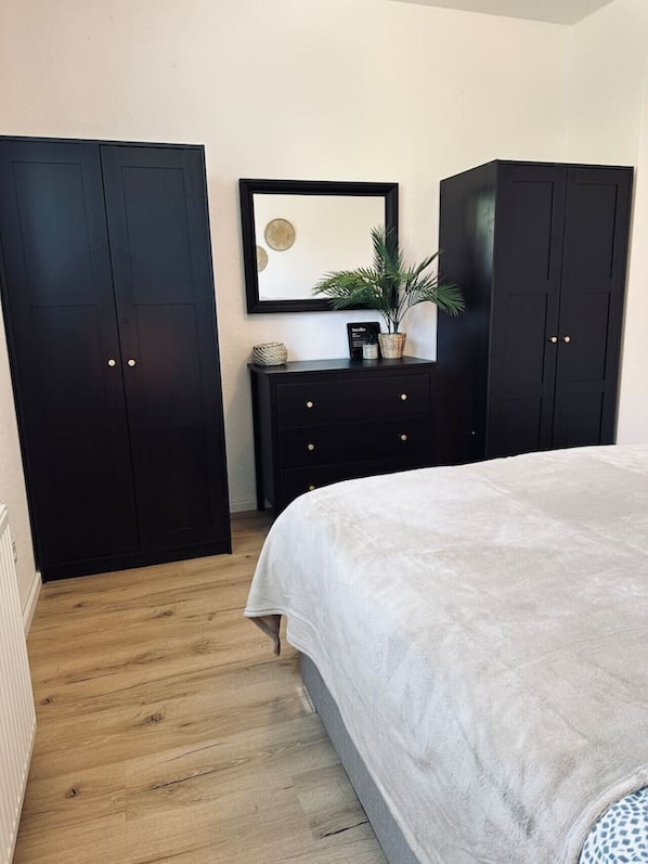 A bedroom with a bed, a dresser, and two wardrobes. - FeWo Am Ring - New Construction & Terrace (Nordhorn)