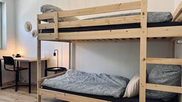 Ein Stockbett mit Schreibtisch und Stuhl, einer Lampe sowie dekorativen Wandbildern.