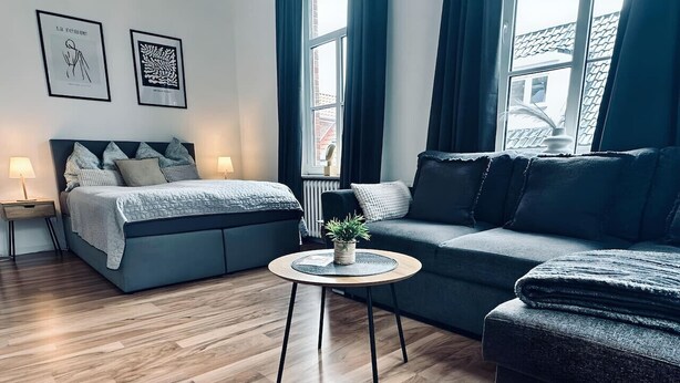 Une chambre à coucher moderne avec un lit, un canapé, une table basse ronde et une plante en pot.