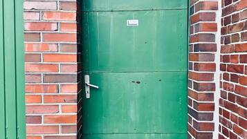 Een groene deur met een bordje, in een bakstenen muur geplaatst.