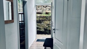 Un couloir étroit, doté d’un plancher en bois, qui mène à un mur de pierre et à une porte.