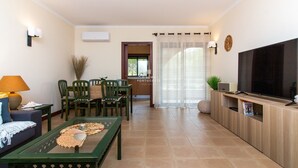 A living room with a sofa, a coffee table, a TV, and a dining area with chairs and a table. - Apartamento do Pinhal by D'Alma Portuguesa (Albufeira)