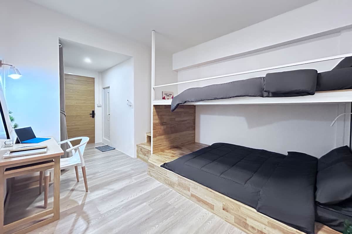 A modern bedroom with a bunk bed, a desk with a laptop, and a chair.