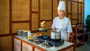 A chef cooking in a traditional kitchen with a bamboo backdrop. - ZEN RETREAT HOI AN (Da Nang)