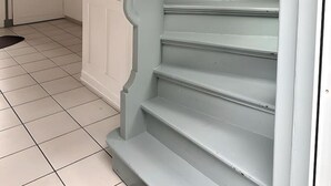 Uma escadaria com paredes e uma porta brancas na base.