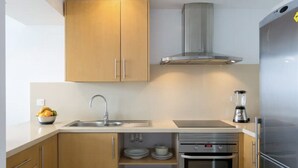 A modern kitchen with wooden cabinets, a stainless steel sink, a built-in oven, and a refrigerator.
