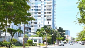 A modern urban street with a multi-story building, parked cars, and well-maintained greenery. - Jlo’s Place/Next to Airport/PrimeLocation/Fastnet (Carolina)