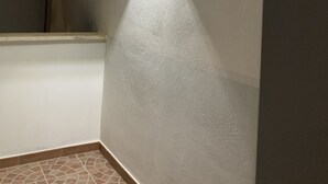 Een hoek van een kamer met een structuurwand, een hoeklamp en een betegelde vloer.