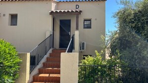 A building with a tiled roof, a door, and a staircase leading to the entrance.
