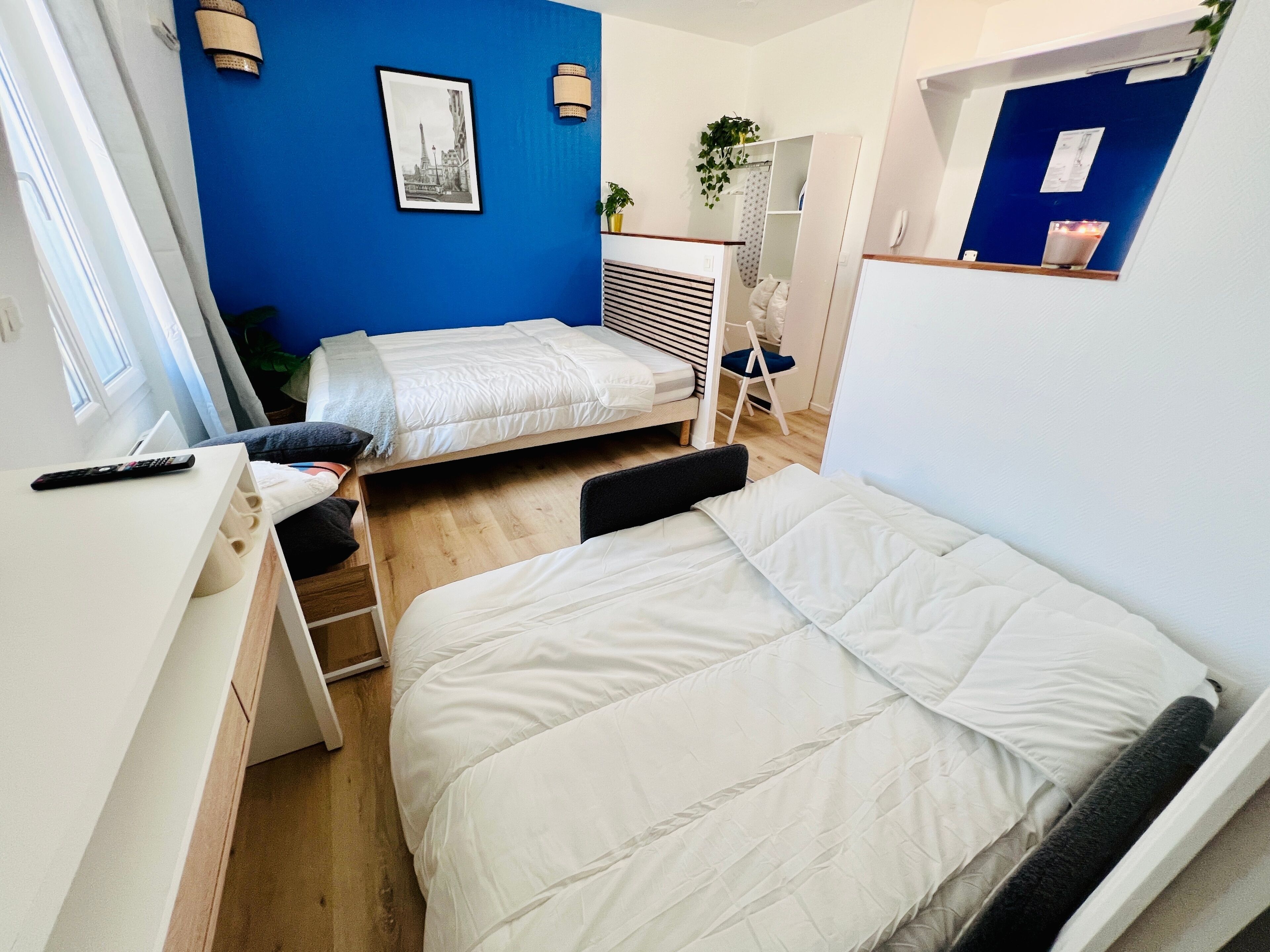 Quarto em dormitório compacto com duas camas individuais, uma escrivaninha e uma cadeira.