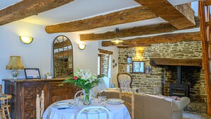 A rustic dining area with a stone fireplace, wooden beams, and a table set for four.