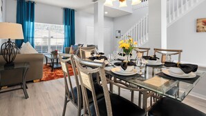 Een moderne eetruimte met een glazen tafel voor zes personen, omringd door houten stoelen met zwarte kussens.