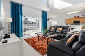 A modern living room with a glass coffee table, black leather sofa, and a brown shag rug. - 5 bed, 3.5 bath newly refurbished villa on the gated community of Westhaven (Davenport)