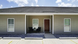 A building with a front porch, two windows, a door, and a small table with chairs. - Welcome!  This apartment offers a spacious and comfortable place to stay.   (Hammond)
