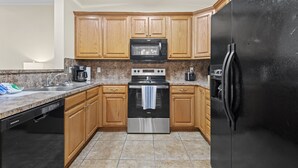 A kitchen with wooden cabinets, a stainless steel stove, a black refrigerator, and granite countertops. - Welcome!  This apartment offers a spacious and comfortable place to stay.   (Hammond)