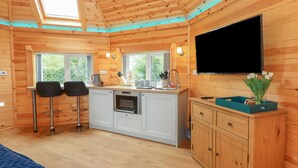 Een compacte keuken met een inbouwoven, een spoelbak en een eethoek met twee stoelen.