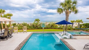 A swimming pool with a view of the ocean, surrounded by palm trees and outdoor furniture. - 34 Surf Scoter at The Sea Pines Resort (Hilton Head Island)