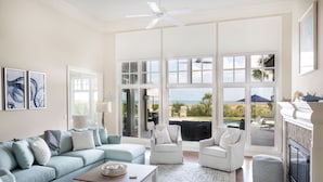 A spacious living room with a large window, a ceiling fan, and a fireplace. - 34 Surf Scoter at The Sea Pines Resort (Hilton Head Island)