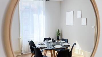 A dining area with a round table, black chairs, and a mirror reflecting the room.