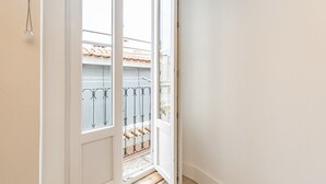 A view from a balcony with a metal railing, a tiled roof, and a clear sky. - Charming Studio Located in the Heart of Lisbon (Lisboa)