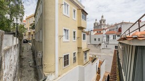 A narrow street with buildings on either side, a staircase on the right, and a church in the background. - Charming Studio Located in the Heart of Lisbon (Lisboa)