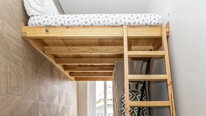 A bunk bed with a ladder, a patterned wall, and a wooden floor. - Charming Studio Located in the Heart of Lisbon (Lisboa)