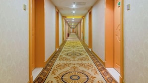 A long, narrow hotel corridor with patterned carpet and orange walls. - Victoria International Hotel (Kaiping Passenger Transport Terminal & Yihua Plaza Branch, Jiangmen) (Kaiping)