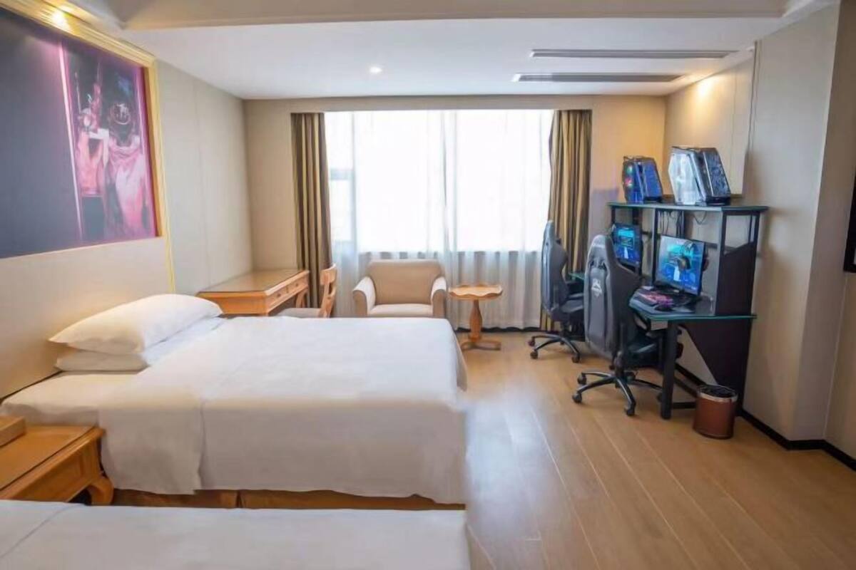 A hotel room with two beds, a desk with a computer, and a small table.
