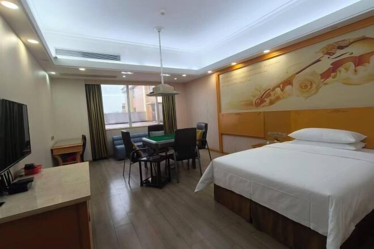 A hotel room with a bed, desk, chairs, and a large wall mural.