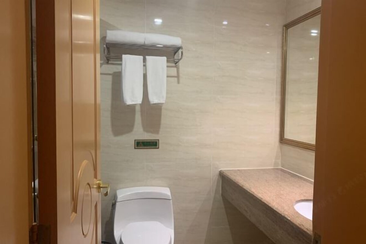 A bathroom with a toilet, a towel rack, a sink, and a mirror.